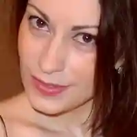 Vana is seen in front of a light wood closet in her filming bedroom. She wears her thin black hair straight and loose. Vana is seen in a strappy top, black eyeliner and a pink gloss lipstick.