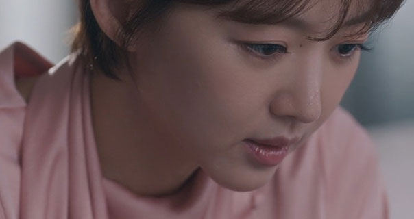 Jang Hee-jin wears a pale pink silk top. She looks down slightly and takes a deep breath.