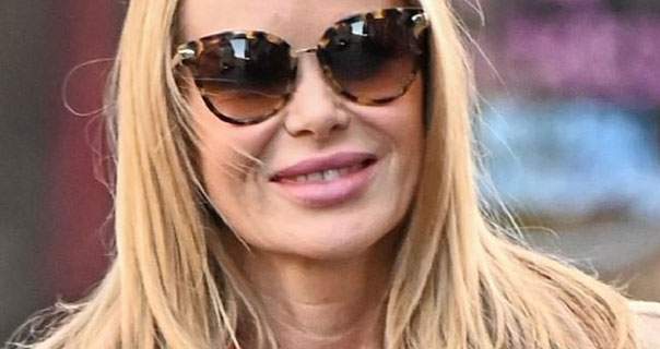 Amanda Holden wears a pair of tortoise shell sunglasses with a long orange coat/