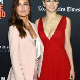 Minka Kelly in a pink suit and silver satin camisole top. She is seen with Alexandra Daddario who wears a red plunge dress.