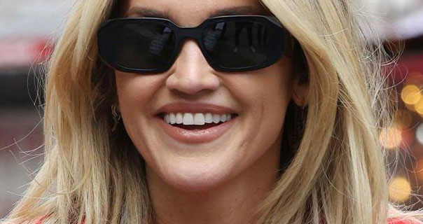 Ashley Roberts smiles as she arrives at Global Studios in London. She wears a pair of black frame sunglasses with her hair loose and straight.