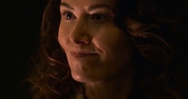 Jewel Staite is seen with her hair loose and curled. She wears a dark pink matte lipstick against a black background.
