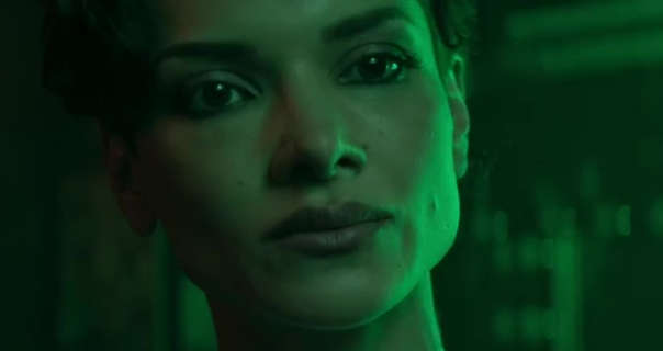 Amber Rose Revah is seen in a green light in a backstage dressing room. She wears her hair short and in natural curls. Amber stars in black eyeliner and a dark lipstick.