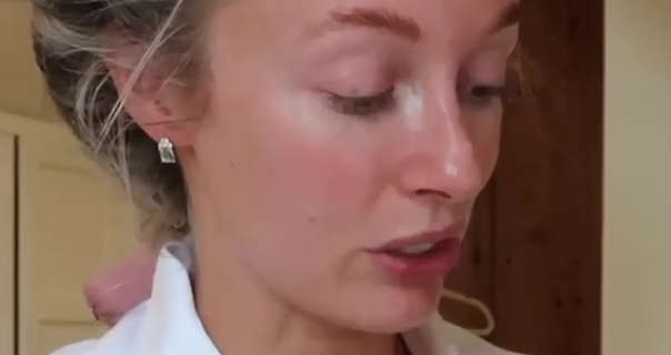 Josie Irons sits in the attic dressing room area of her country home. She is seen in front of wood beams and cream storage wardrobes. Josie wears her hair pinned back and wrapped in a sausage roller. She is seen with light foundation, blush and a pair of small silver gold earrings.