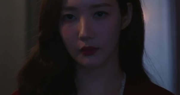 Park Min-young appears in a dark room in front of a large window and a closed sheer white curtain. She wears her long black hair loose and down around her shoulders. Park Min-young is seen in a dark red matt lipstick and a white lace trim silk robe.