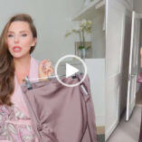 A split screen view of Laura Blair. Laura is seen in a pink floral dressing gown holding a maroon outfit on a hanger. Her hair is loose and in gentle waves. Laura wears a glossy pink lipstick with pink eye shadow and black mascara. The cutaway shows her wearing the halter top and trousers maroon ensemble. She captures the look in an iPhone in a purple case.