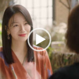 Baek Eun-hye sits in a large restaurant eating area in front of green trees and leafy plants. She appears with her black hair down and straightened. Baek Eun-hye wears a light foundation with earrings and a red lipstick.