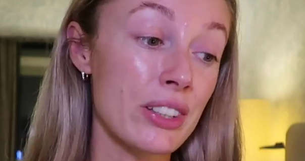 Josie Fear looks down and to the side. She sits in a light green and dark wood hotel room. Josie has her long blonde hair loose and tucked behind her ears. She wears no makeup as she gets ready to sleep.