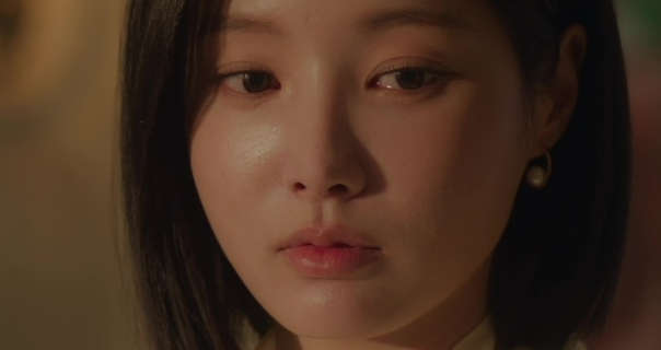 Yeonwoo is seen in a dark room cast in an orange glove from lamplight. She has her black hair cut short and straightened. Yeonwoo stars in a pair of pearl earrings and a light pink lipstick.