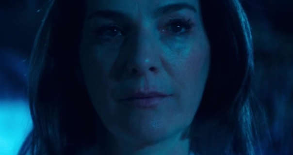 Ayelet Zurer is seen in cast in ethereal moonlight at nighttime. She has her long hair loose and slightly curled. Ayelet wears mascara with a soft blush as light makeup.